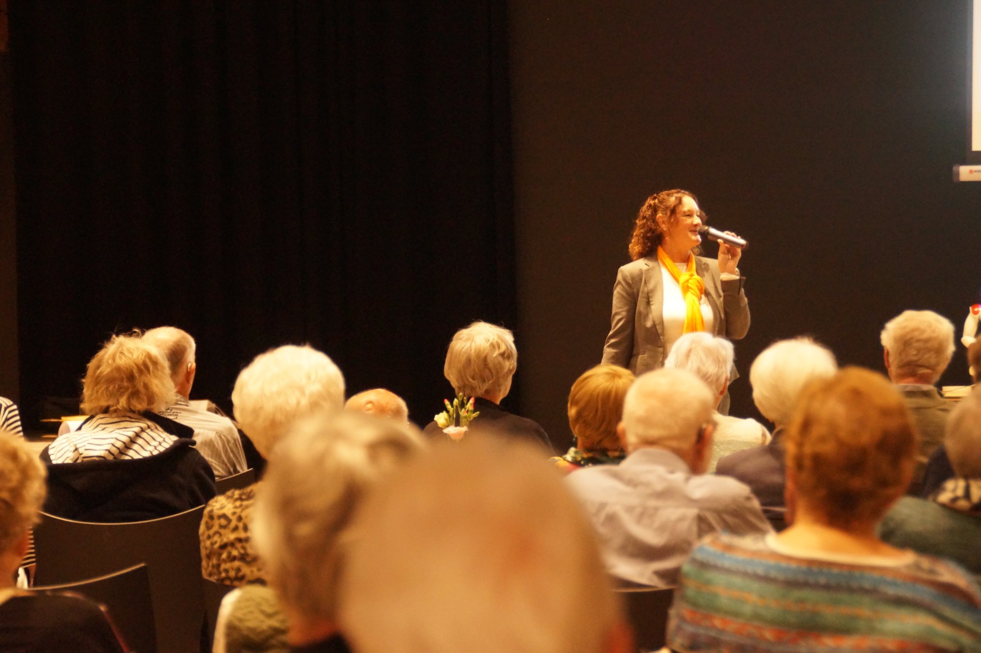 Helma Lensen aan het spreken op het podium voor een zaal